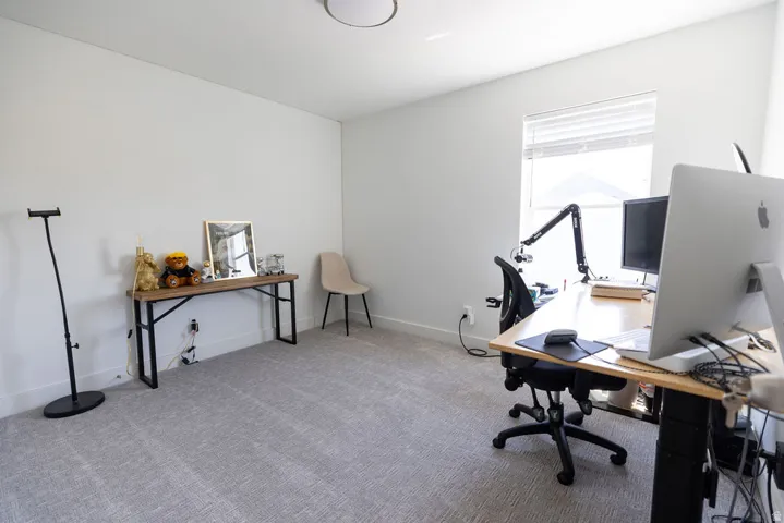 Spacious room featuring light gray carpet, white walls, and a window with horizontal blinds