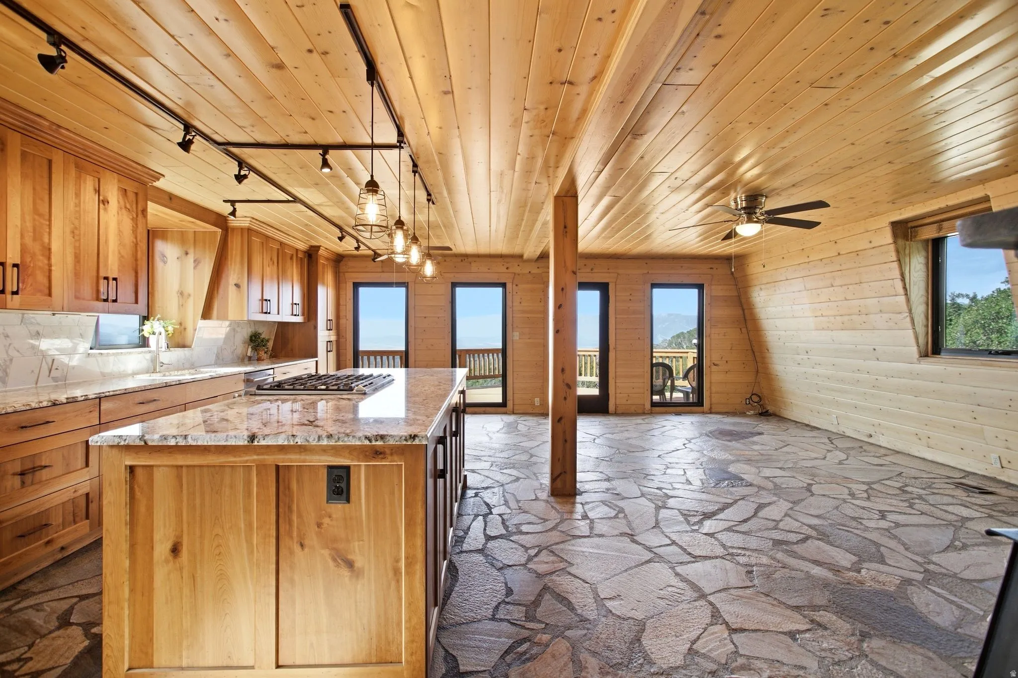 Gourmet kitchen with custom wood cabinetry, stone countertops, and a central island with a built-in gas range