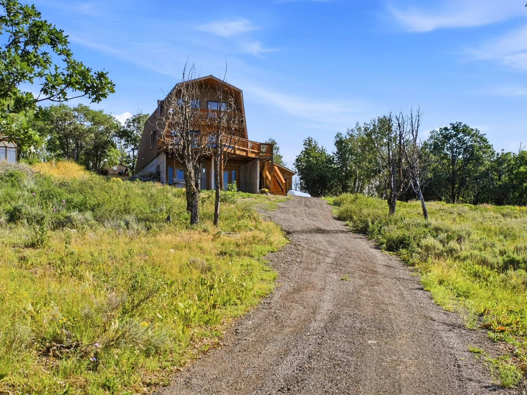Wood-sided structure featuring multiple levels, a prominent deck, and varied window placements