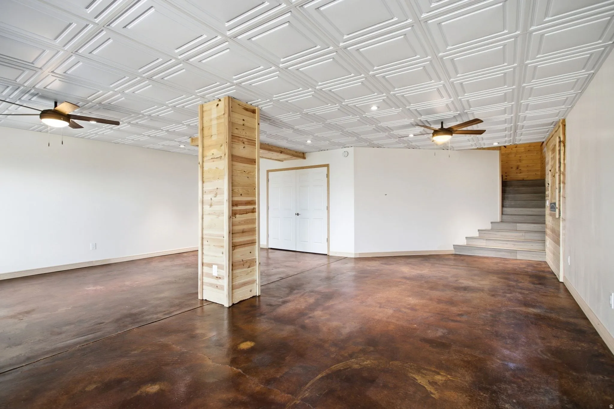 Spacious room featuring distressed concrete flooring and a white coffered ceiling with recessed lighting