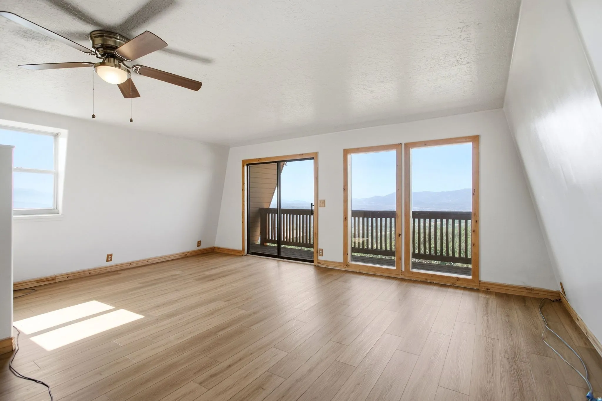 Spacious Primary Bedroom featuring wood-finish flooring, a contemporary ceiling fan, and a large window