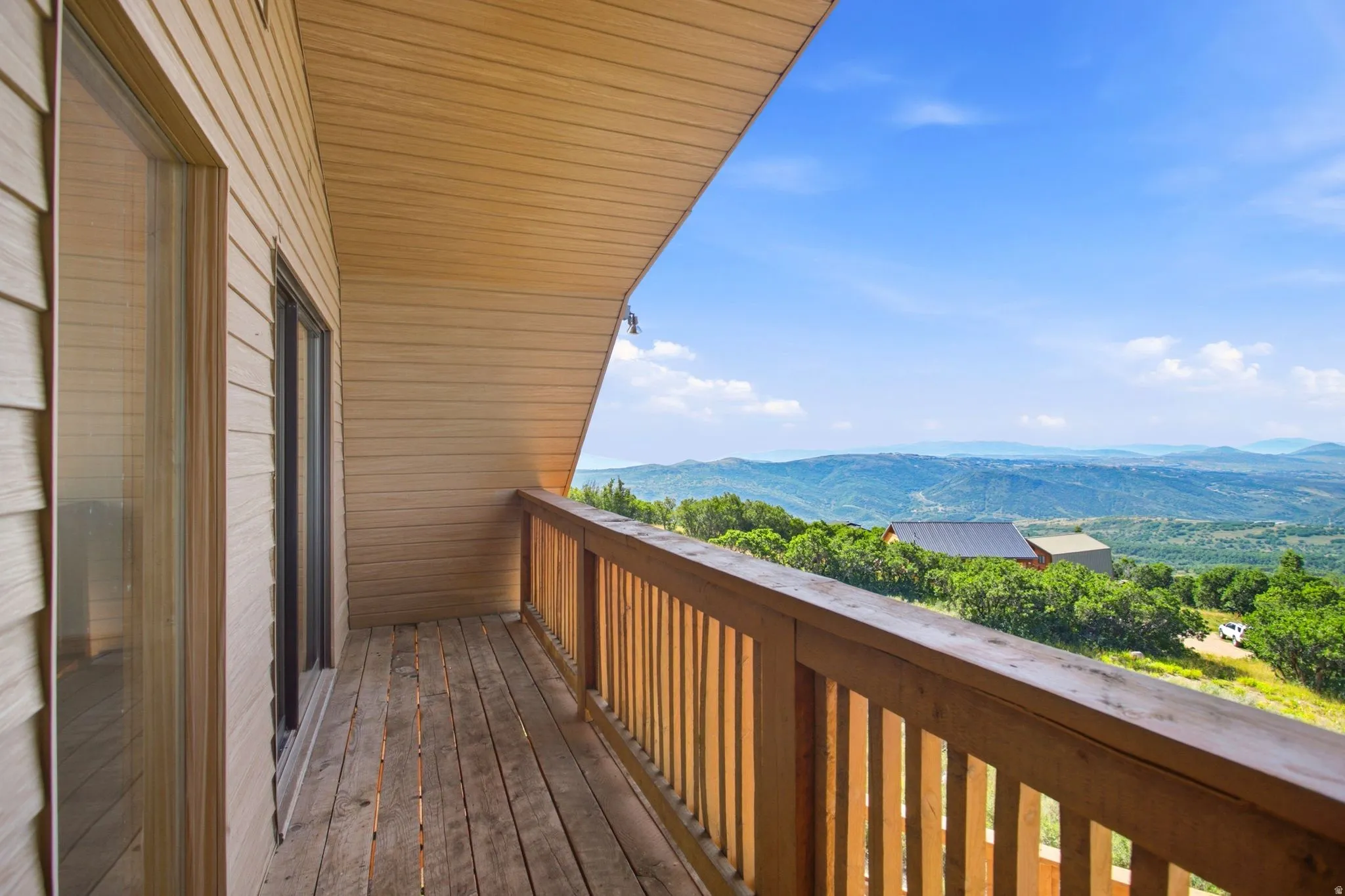 Private wood-plank balcony with wood railing, offering expansive mountain scenery