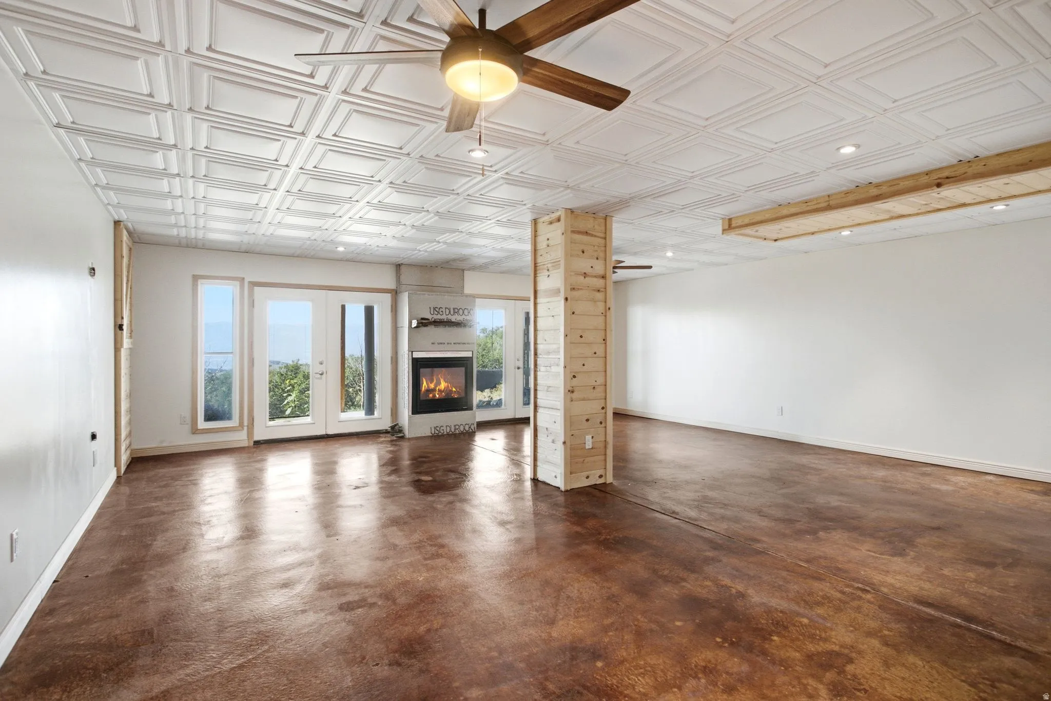 Spacious interior featuring a coffered ceiling, wood-finish flooring, a contemporary fireplace, and multiple glass-paned doors
