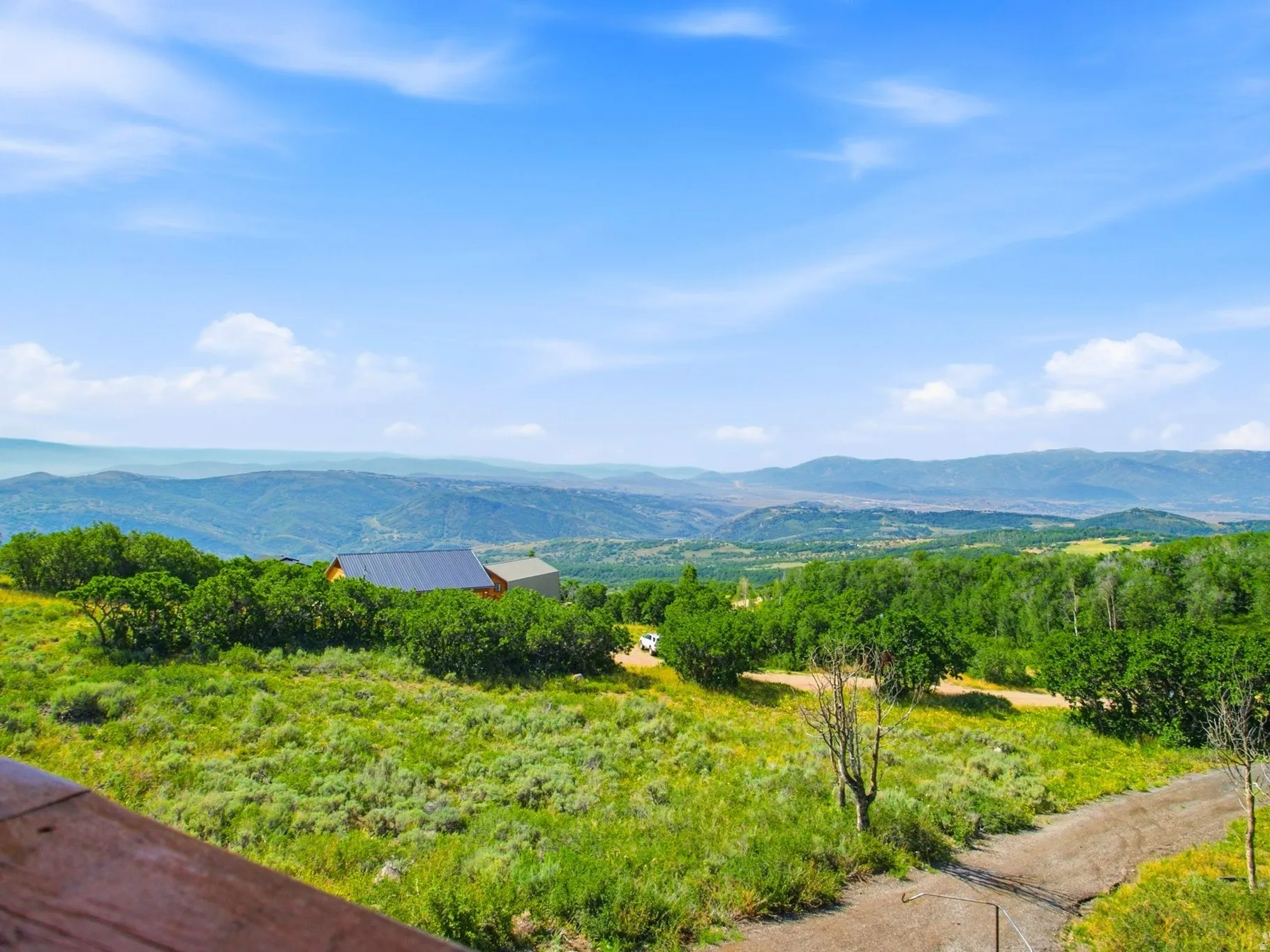 Expansive mountainous terrain with distant buildings and lush green foliage