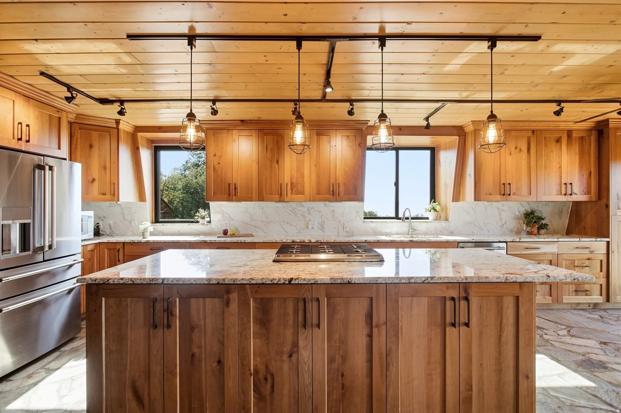 Kitchen featuring a large central island with an integrated cooktop, granite countertops, and wood cabinetry