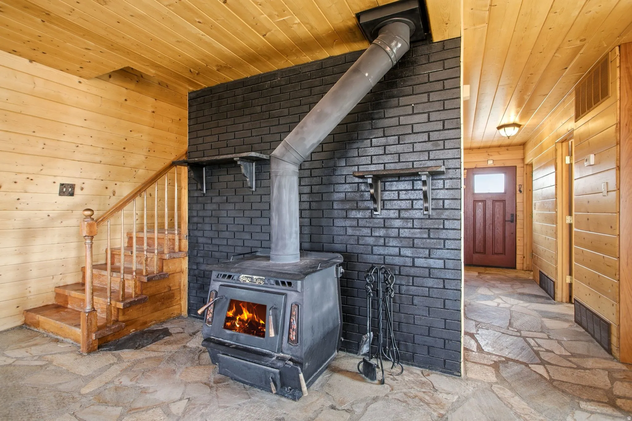Stairway, Wood-burning stove with a metal flue pipe, set against a dark brick accent wall