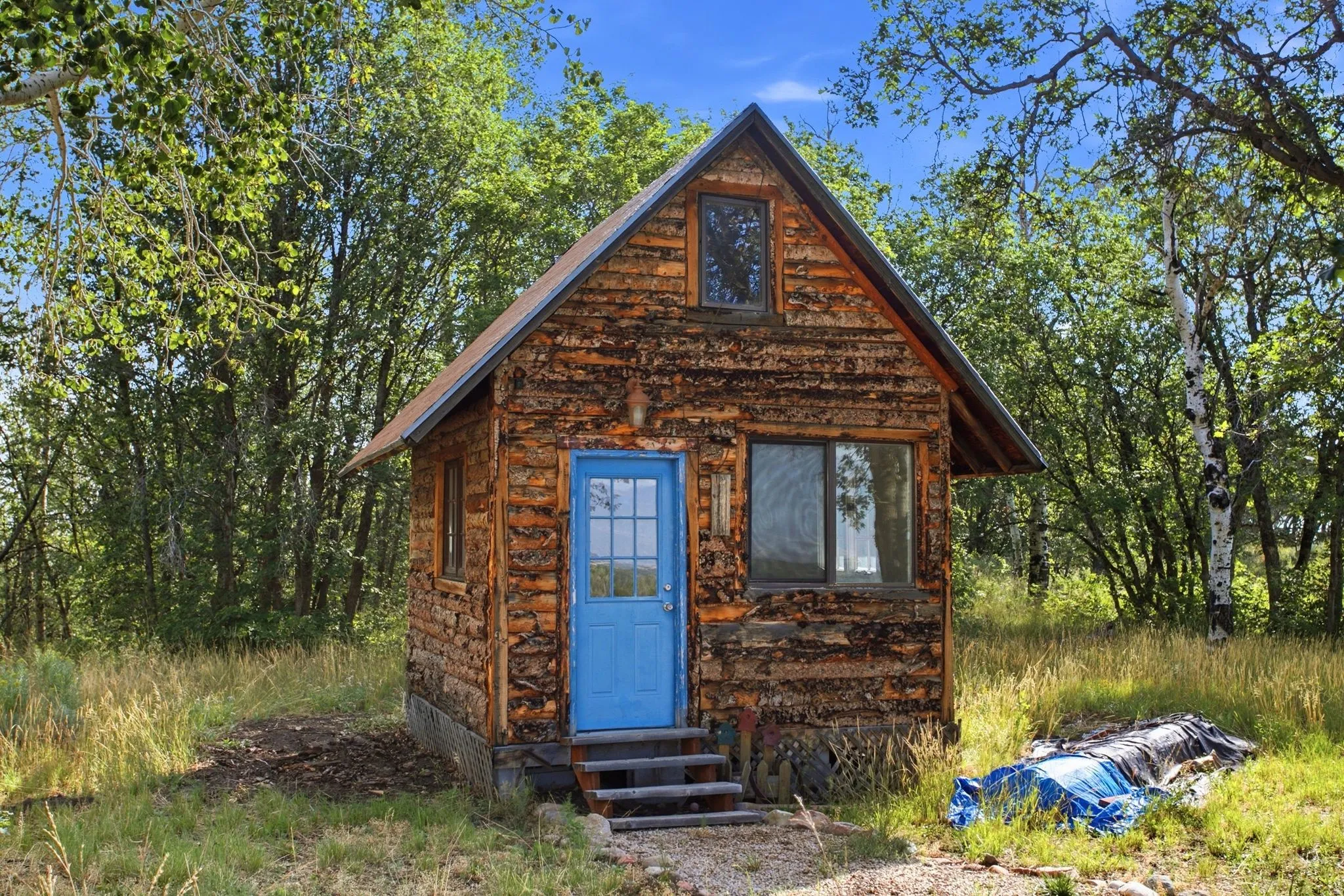 Rustic cabin/office/playhouse exterior featuring log siding and an A-frame roofline