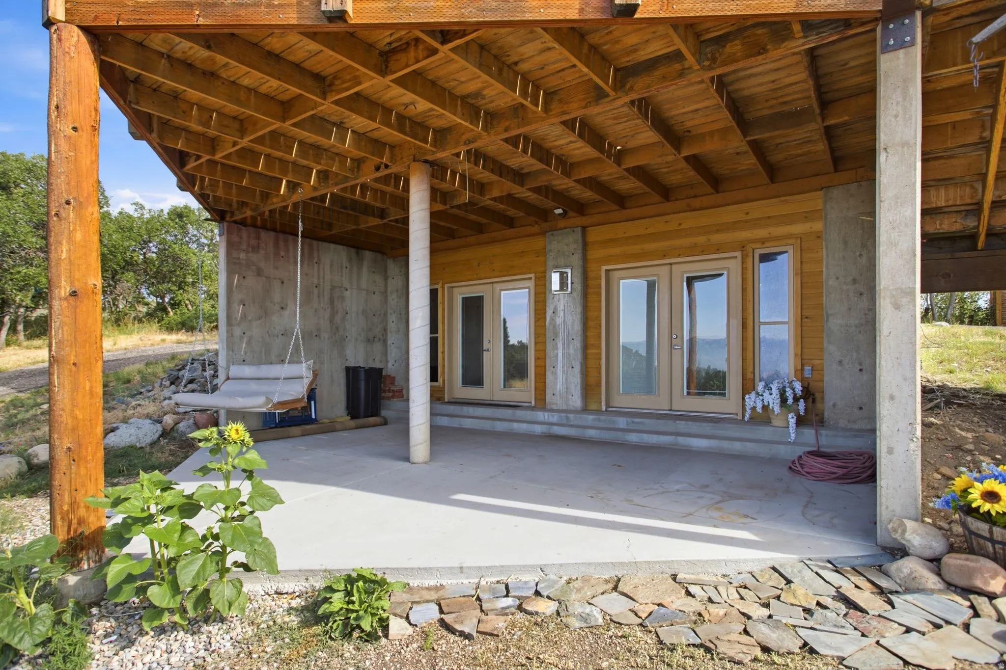 Covered patio with a concrete slab, wooden ceiling, and concrete support columns