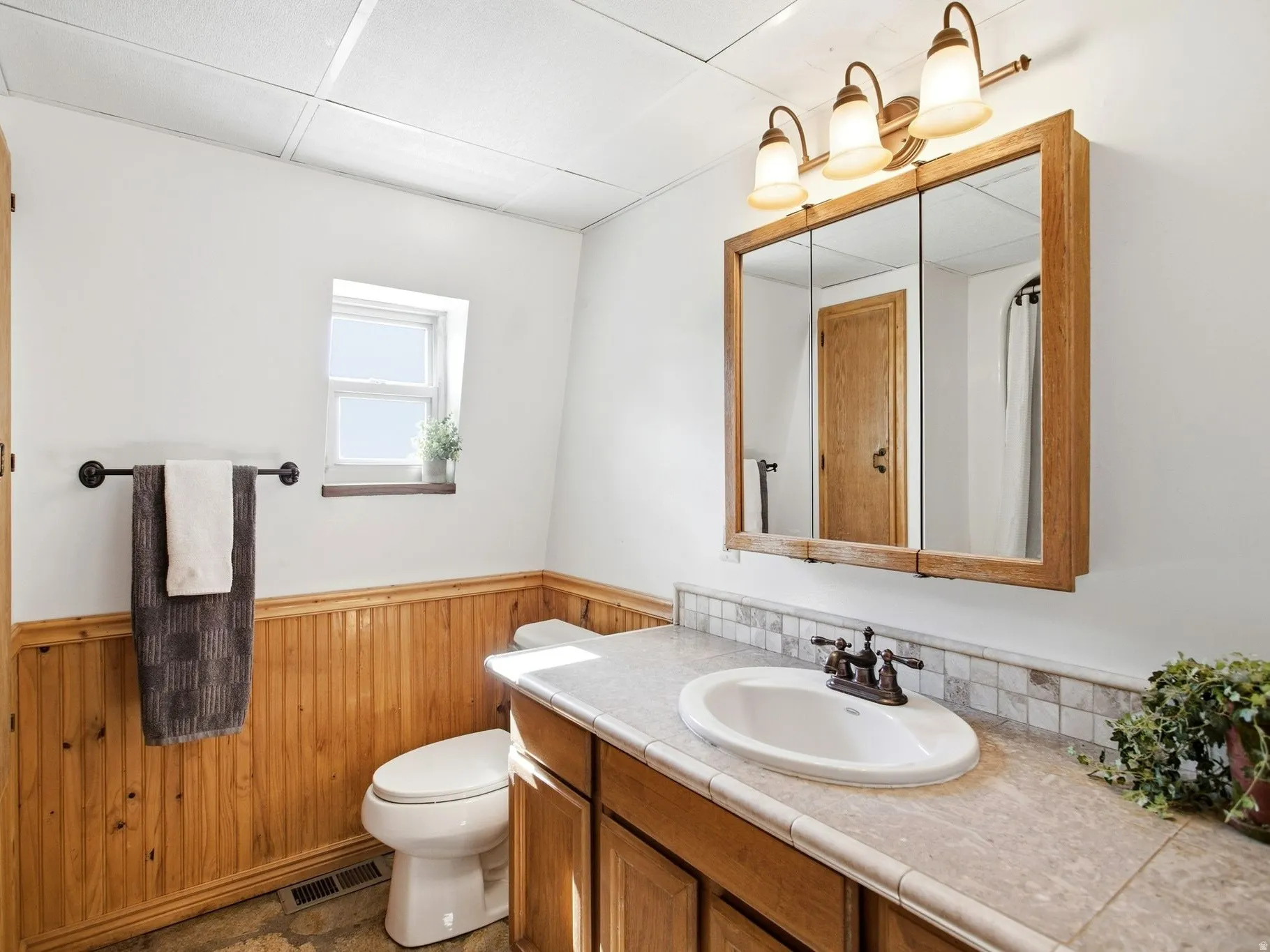 Full bathroom featuring wood-finish beadboard wainscoting and a matching wood-finish vanity