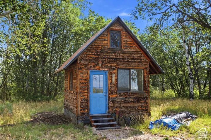 Rustic cabin/office/playhouse exterior featuring log siding and an A-frame roofline