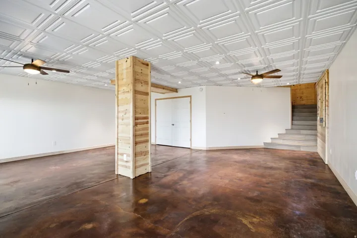 Spacious room featuring distressed concrete flooring and a white coffered ceiling with recessed lighting