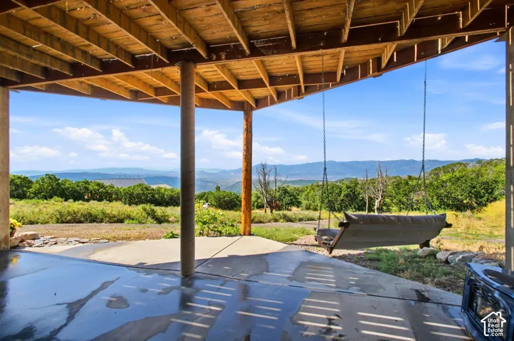Covered concrete patio with exposed wood joist ceiling, supported by rustic posts