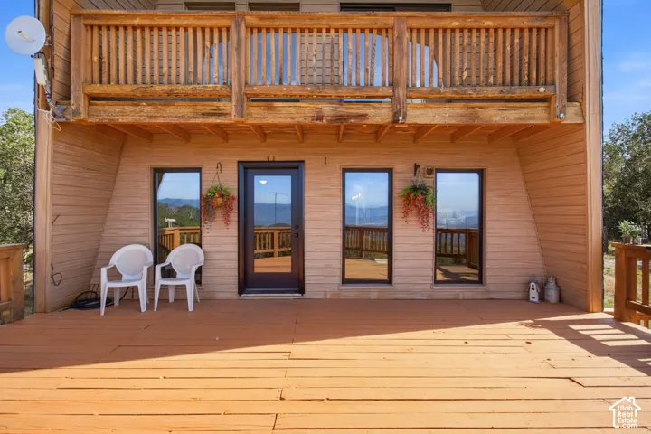 Expansive wood deck with a full-light entry door and three windows, featuring a wood-plank exterior and an upper-level wood balcony