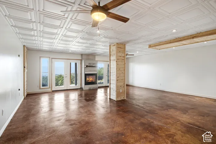 Spacious interior featuring a coffered ceiling, wood-finish flooring, a contemporary fireplace, and multiple glass-paned doors