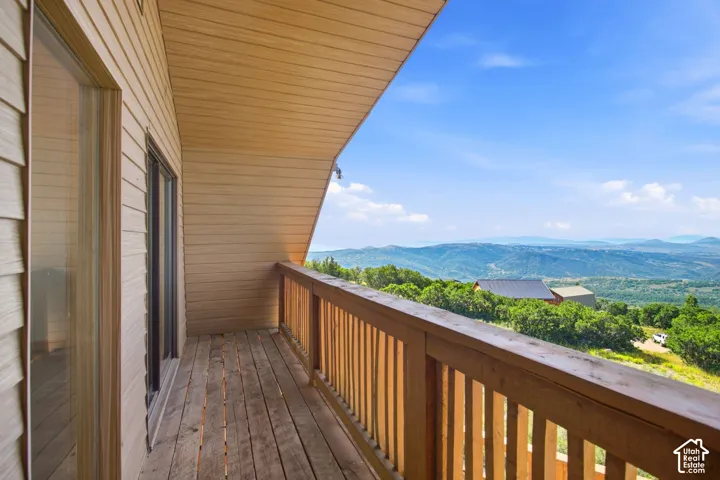 Private wood-plank balcony with wood railing, offering expansive mountain scenery
