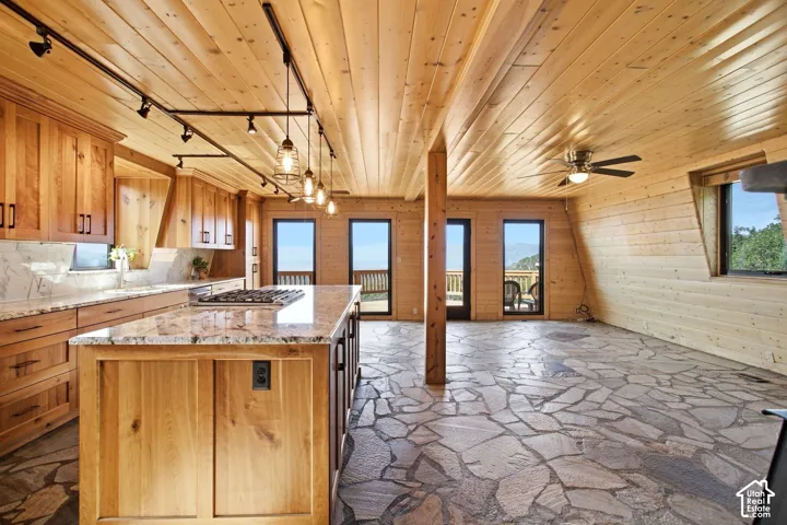 Gourmet kitchen with custom wood cabinetry, stone countertops, and a central island with a built-in gas range