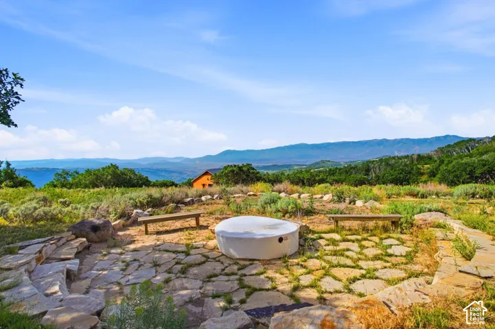 Stone patio area featuring a propane fire pit, surrounded by two wooden benches and additional stone seating