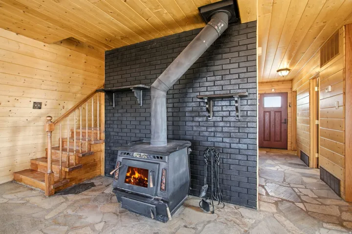 Stairway, Wood-burning stove with a metal flue pipe, set against a dark brick accent wall