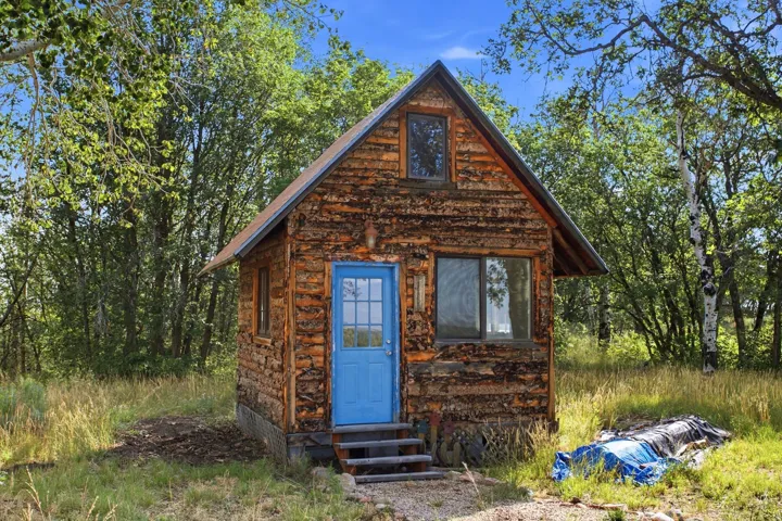 Rustic cabin/office/playhouse exterior featuring log siding and an A-frame roofline