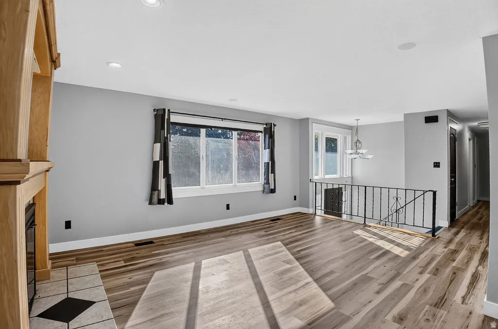 Open-concept interior featuring wood-finish flooring, recessed lighting, and a fireplace with a tiled hearth and wood mantel