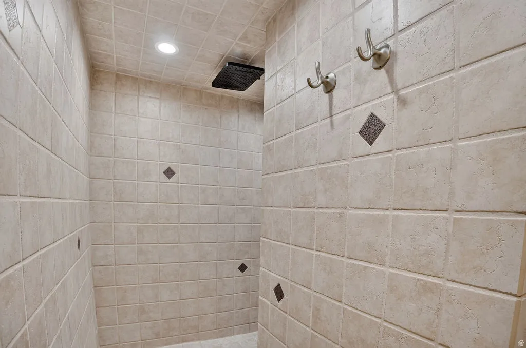 Tiled shower stall featuring square beige tiles with accent diamond-patterned inserts
