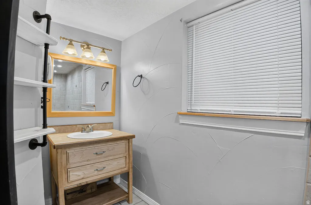 Bathroom featuring a wood-finish vanity with an integrated sink and light-toned countertop