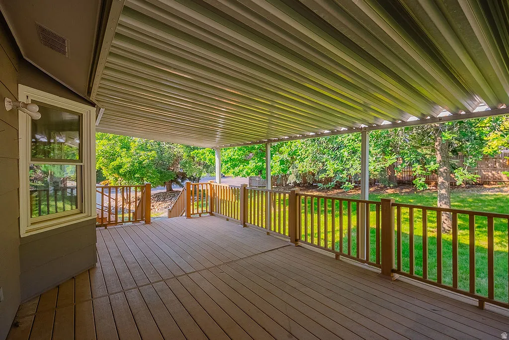 Spacious covered deck featuring composite decking, wood railings, and a white metal patio cover