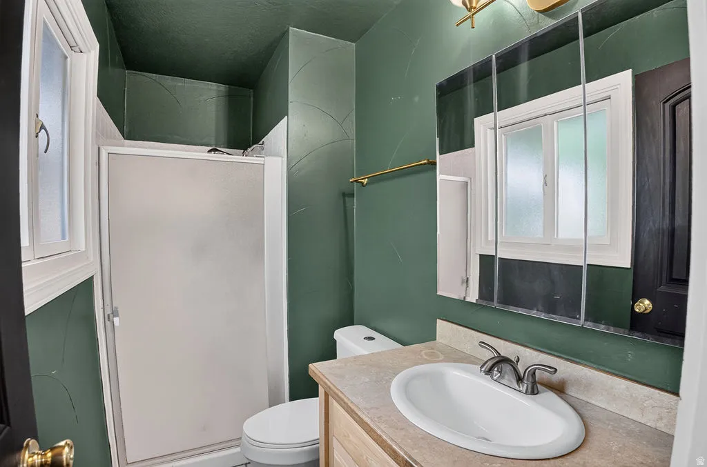 Bathroom featuring a shower with a frosted glass enclosure, a single vanity with an integrated sink and light-colored countertop, and a mirrored medicine cabinet