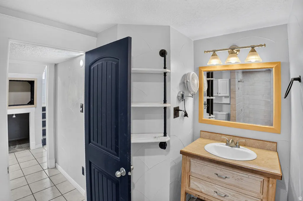 Light wood-finish vanity with an oval basin, framed mirror, and three-light fixture
