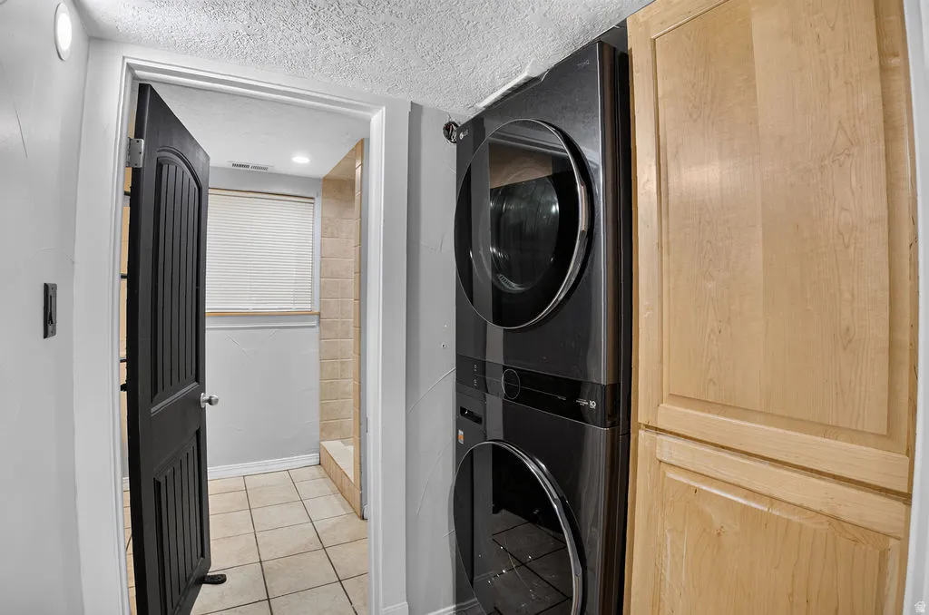 Stacked washer and dryer unit with adjacent light wood-finish cabinetry