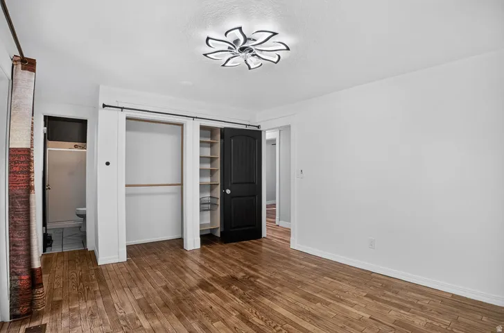 Room featuring wood-finish flooring, white walls, and a modern ceiling light fixture