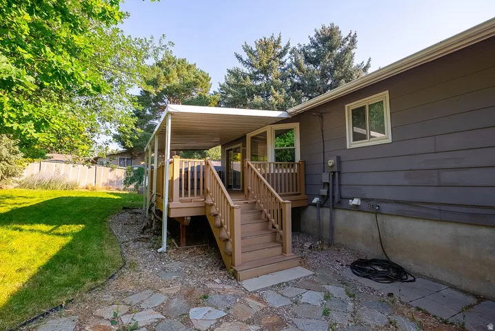 Outdoor living space featuring a covered deck with natural wood railings, stairs, and a flagstone patio