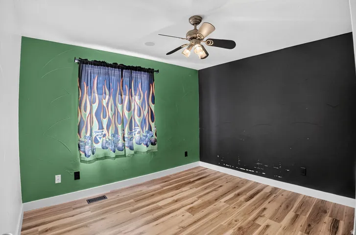 Room with wood-finish flooring, a window, and a ceiling fan with integrated lighting