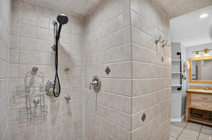 Tiled shower enclosure featuring a handheld showerhead and built-in fixtures