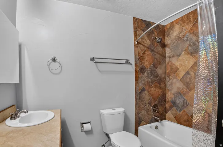 Bathroom featuring a tub/shower combination with multi-toned diamond-patterned wall tiling