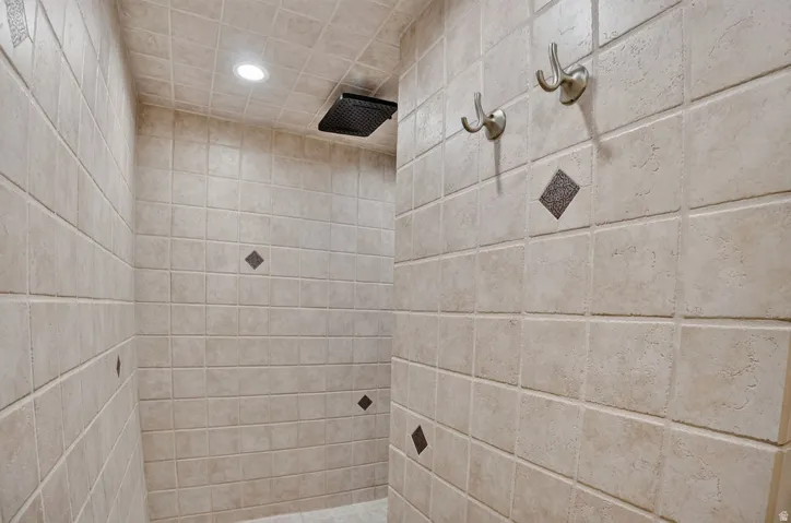 Tiled shower stall featuring square beige tiles with accent diamond-patterned inserts