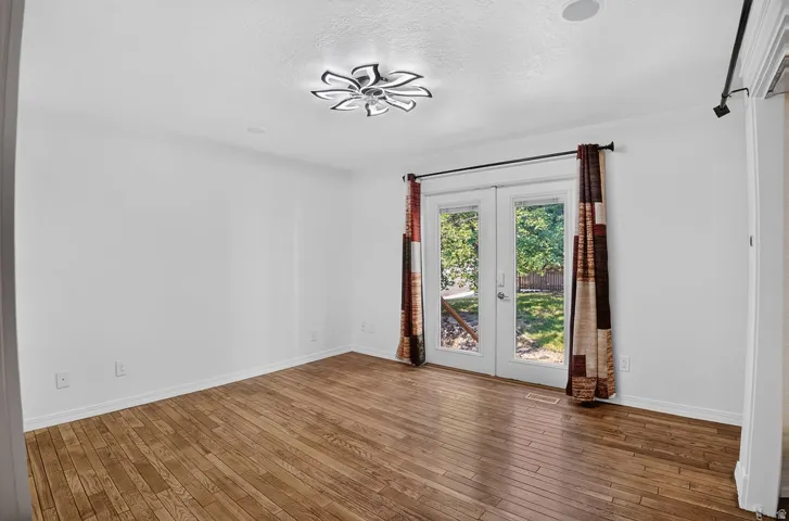 Room with wood-finish flooring, white walls, and a contemporary ceiling light fixture