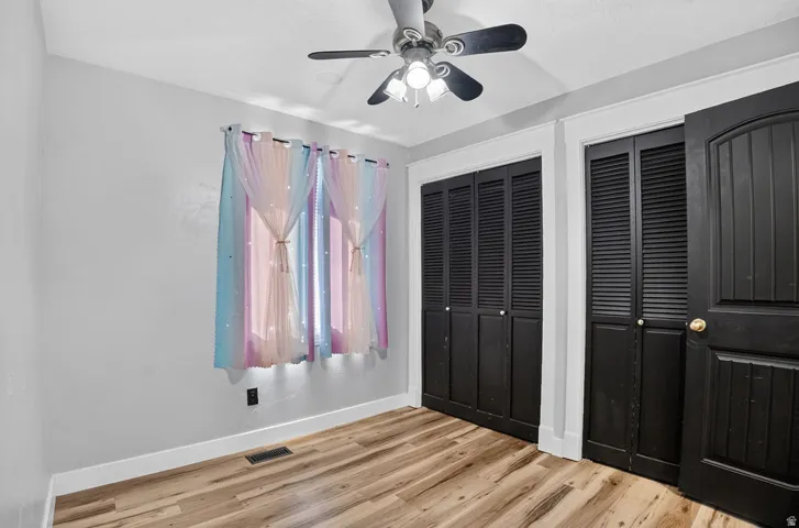 Room featuring wood-finish flooring, light grey walls, and white trim