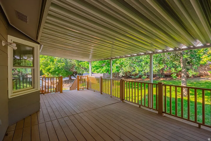 Spacious covered deck featuring composite decking, wood railings, and a white metal patio cover