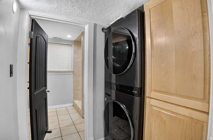 Stacked washer and dryer unit with adjacent light wood-finish cabinetry