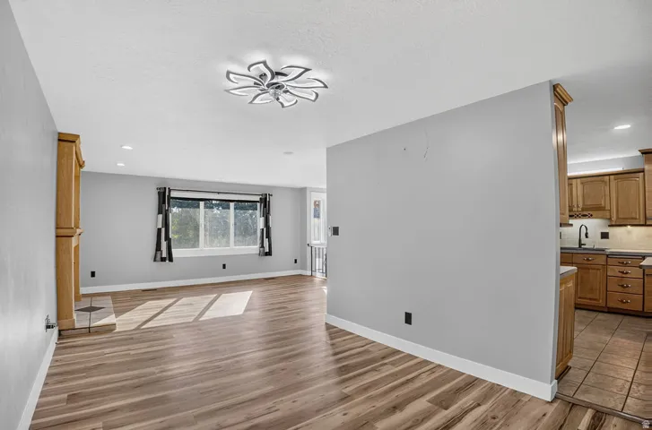 Open-concept living space featuring wood-finish flooring, recessed lighting, and a prominent decorative ceiling fixture