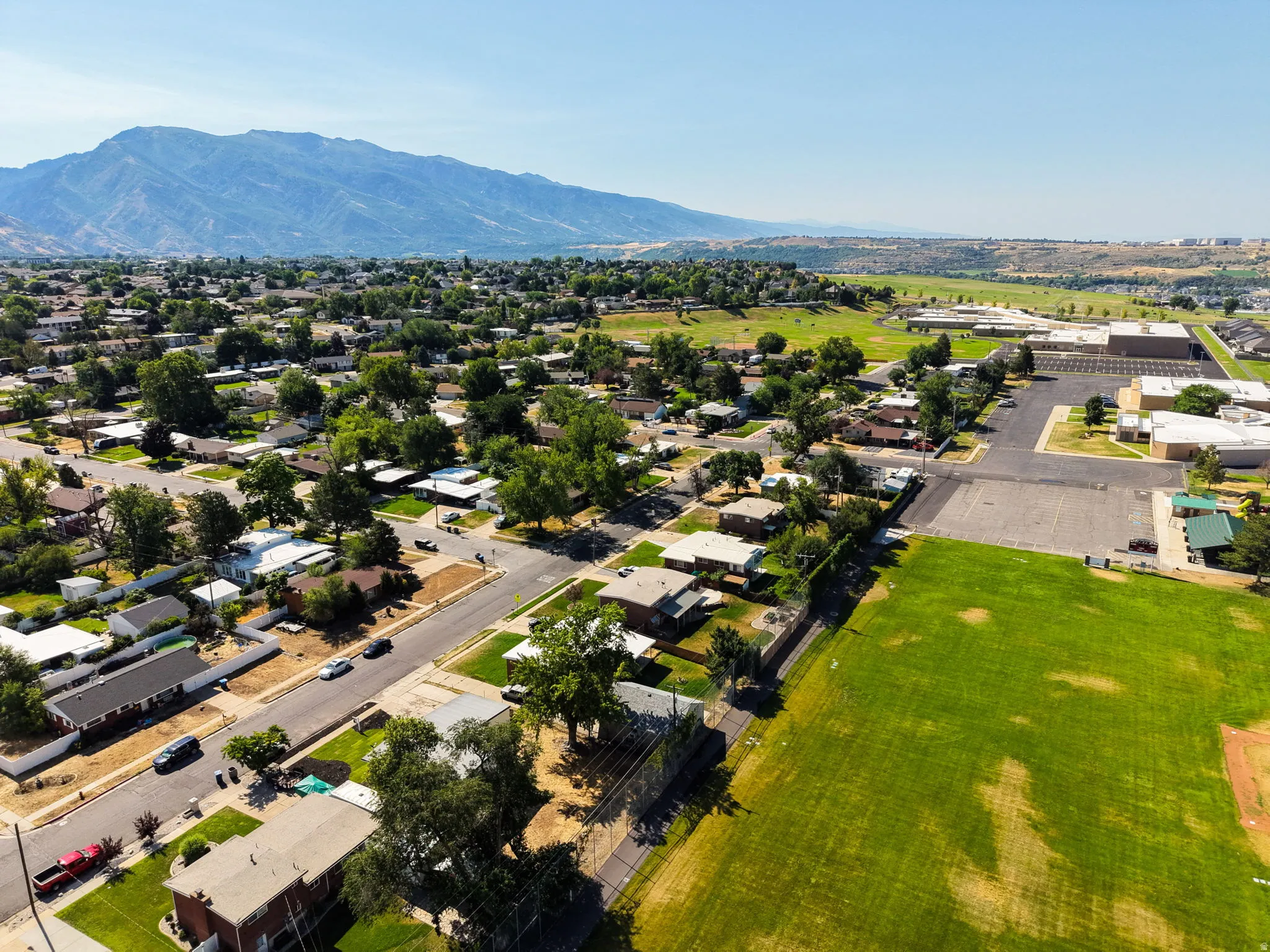 Expansive aerial view showcasing a residential area with varied housing styles, mature trees, and paved streets
