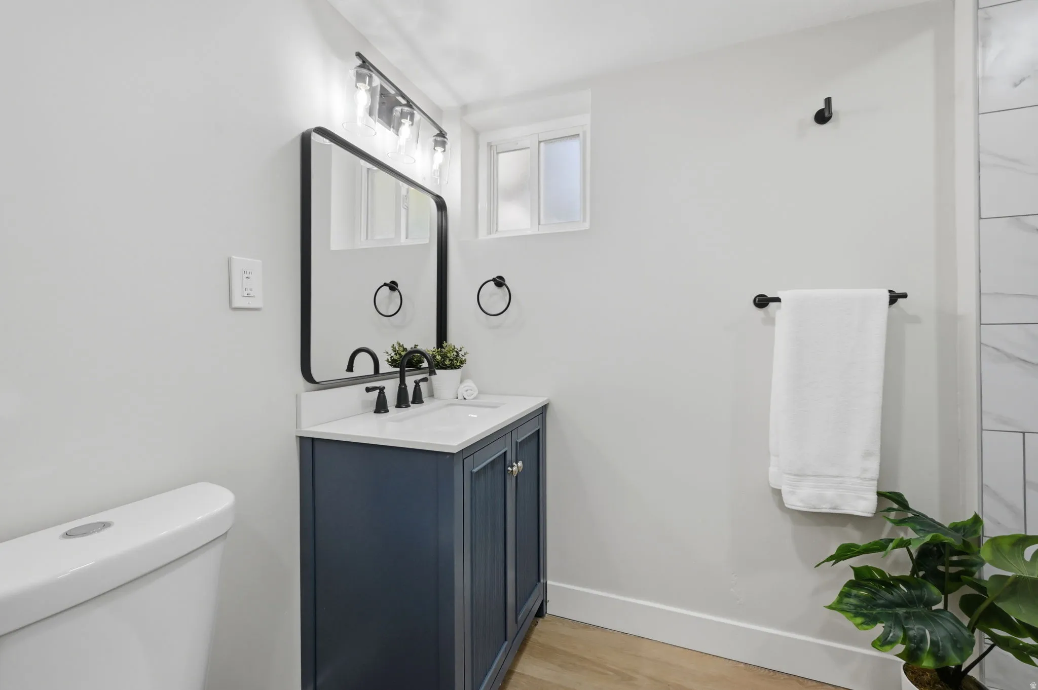 Bathroom vanity featuring a navy blue cabinet with black hardware, a white countertop with an integrated sink, and a black faucet
