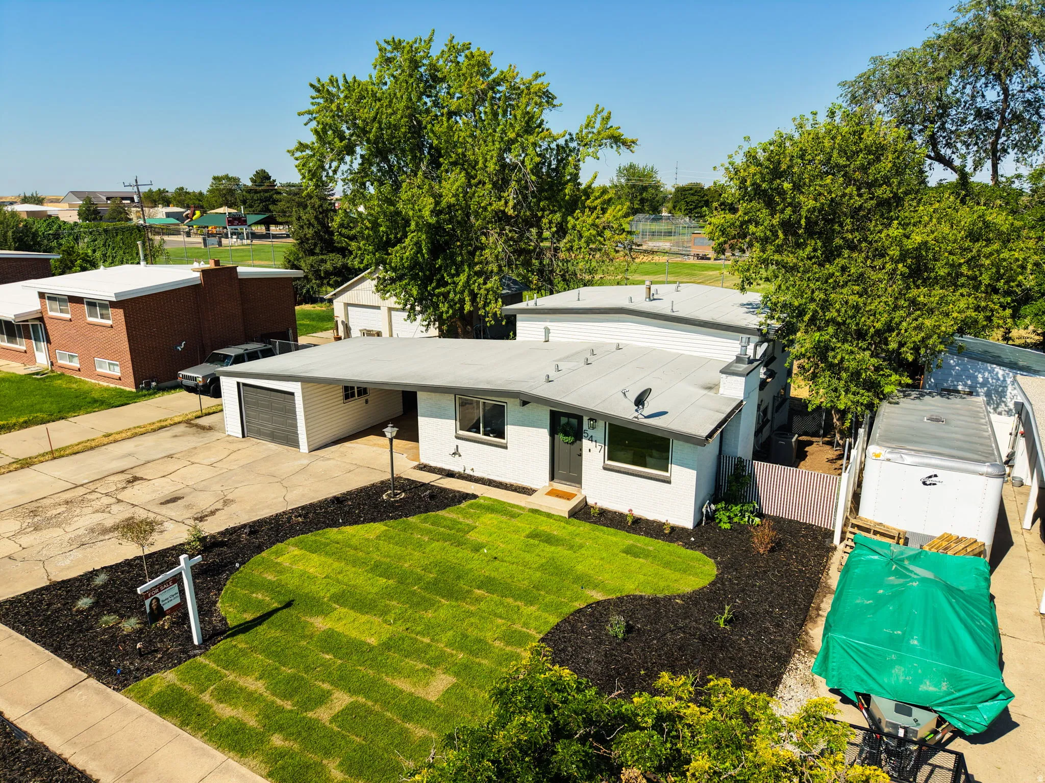 Contemporary white exterior with a flat roofline, attached carport, and a dark garage door