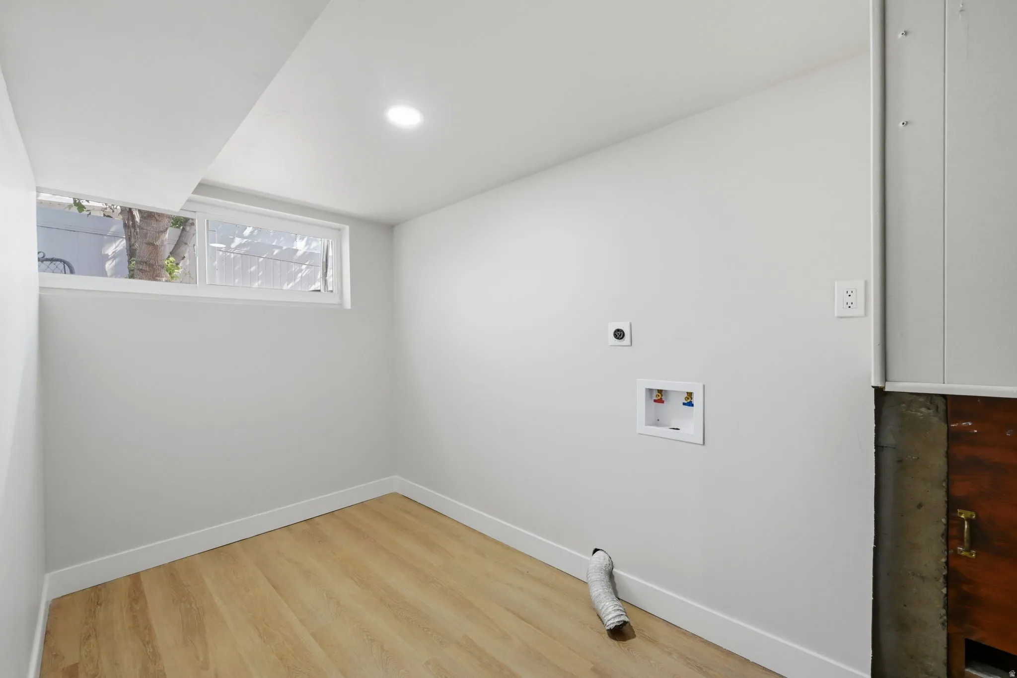 Laundry space featuring a utility hookup, light wood-finish flooring, recessed lighting, and a horizontal window
