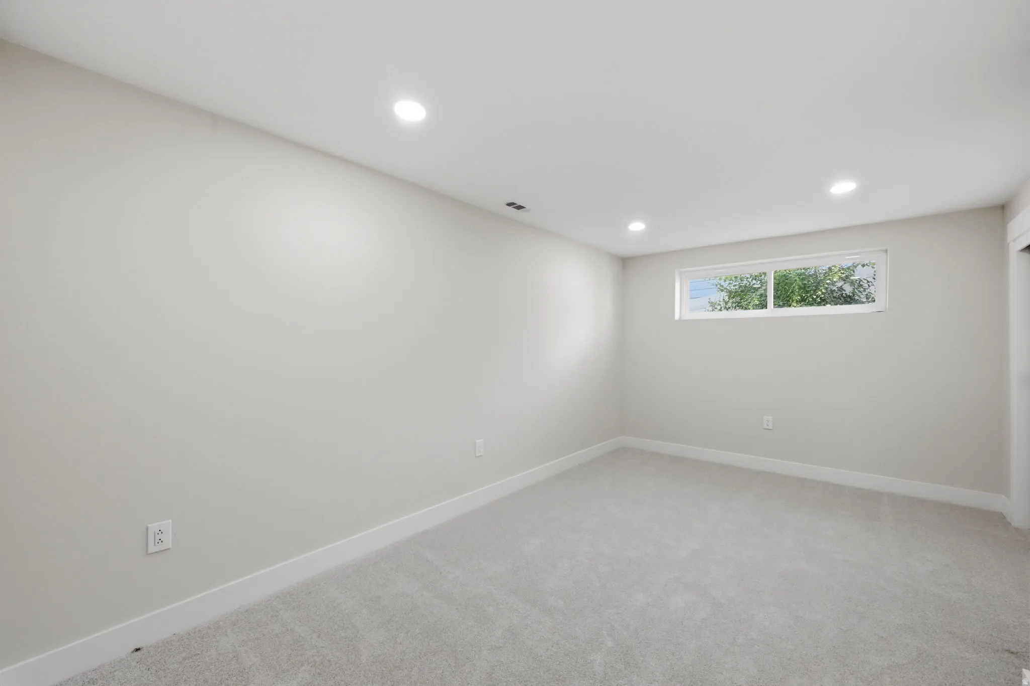 Spacious room featuring light gray carpeting and white baseboards