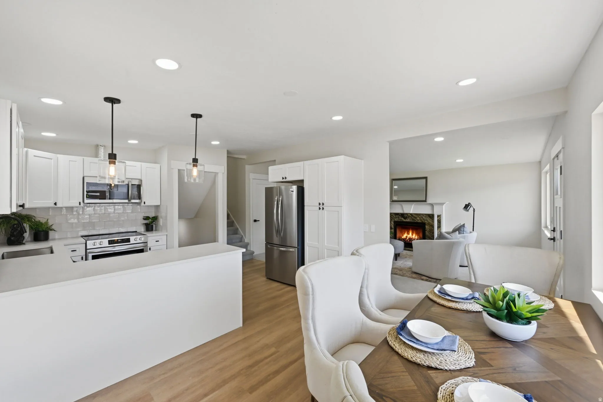 Modern kitchen featuring white cabinetry, stainless steel appliances, a white subway tile backsplash, and light wood-finish flooring