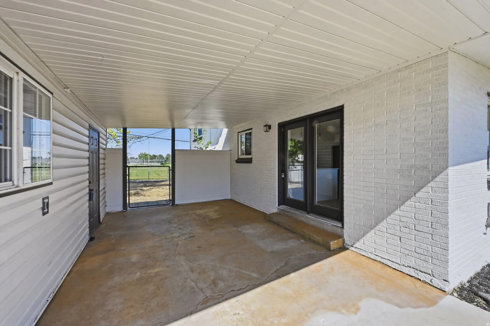 Covered patio featuring a concrete floor, painted brick exterior, and vinyl siding