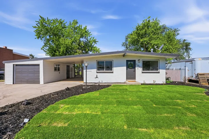 Single-story residence featuring a carport and attached garage with a dark gray door