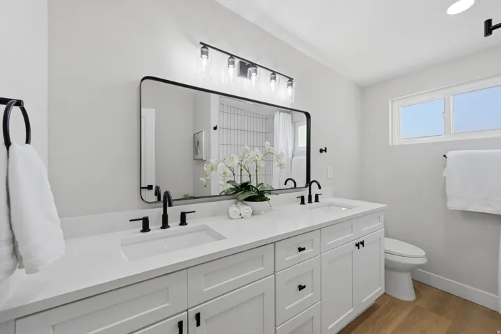 Double vanity featuring white shaker cabinetry and integrated rectangular sinks